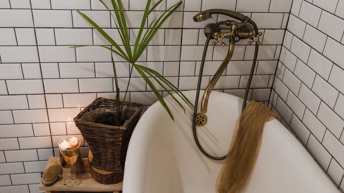 Vintage-style bathtub with candles and plant decor in a cozy tiled bathroom